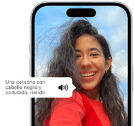 Un iPhone 15 muestra la funcionalidad VoiceOver describiendo una imagen, Una persona con pelo negro ondulado sonriendo